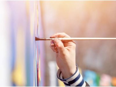 Close-up of a girl’s hand painting on canvas.